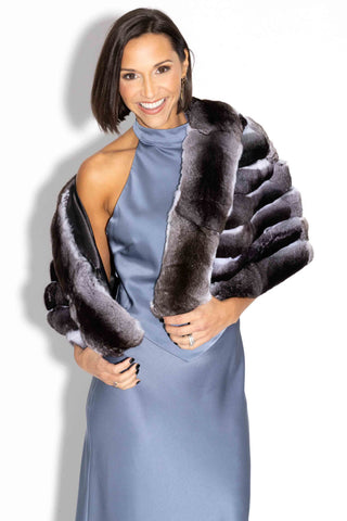 woman wearing a chinchilla fur cape against a white backdrop, smiling
