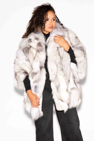 woman wearing a blue sectioned fox fur capelet against a white backdrop