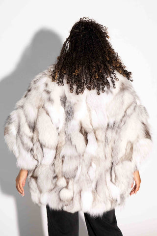 back of woman wearing a blue sectioned fox fur capelet against a white backdrop