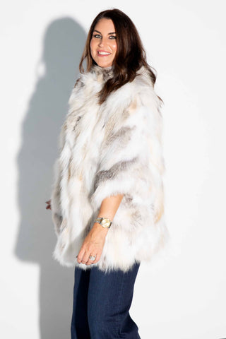 side profile of woman wearing a golden island sectioned fox fur capelet against a white backdrop