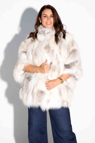 smiling woman wearing a golden island sectioned fox fur capelet against a white backdrop