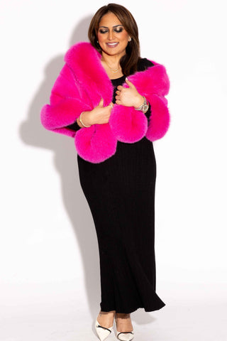 woman wearing a hot pink mink fur cape with fox fur trim against a white backdrop