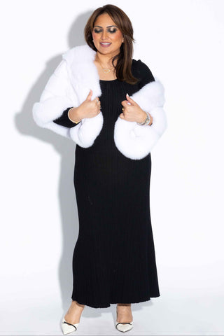 woman wearing a white mink fur cape with fox fur trim against a white backdrop