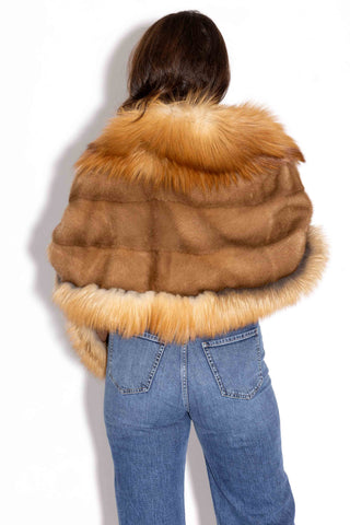 back of woman wearing whisky mink fur cape with natural red fox fur trim against a white backdrop