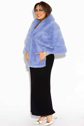 wider shot of a side profile of a smiling woman wearing a baby blue mink fur stole with shawl collar against a white backdrop