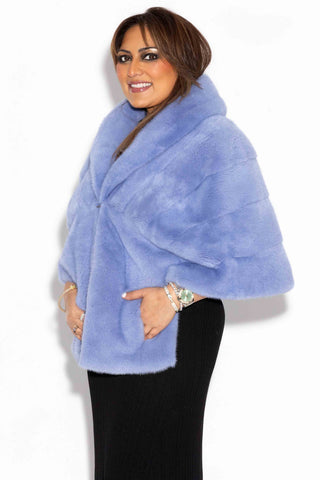 side profile of a smiling woman wearing a baby blue mink fur stole with shawl collar against a white backdrop