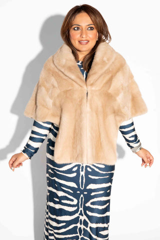 woman wearing a beige mink fur stole with shawl collar against a white backdrop