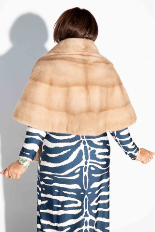 back of woman wearing a beige mink fur stole with shawl collar against a white backdrop