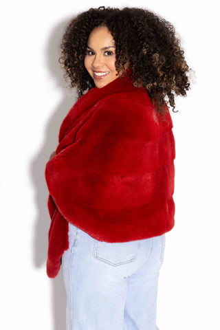 side profile of a woman wearing a red mink fur stole with shawl collar against a white backdrop