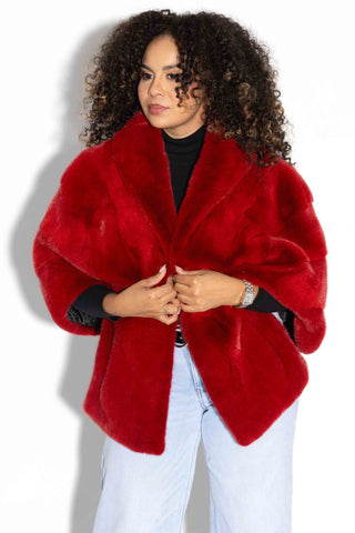 woman with curly hair wearing a red mink fur stole with shawl collar against a white background