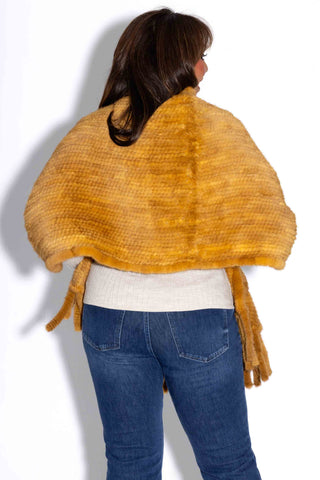 back of woman wearing a whisky knitted mink fur shawl against a white backdrop