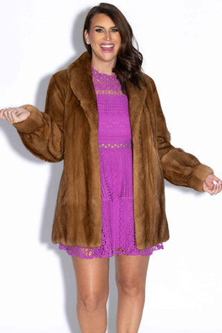 smiling woman wearing a whisky mink fur jacket with shawl collar against a white backdrop