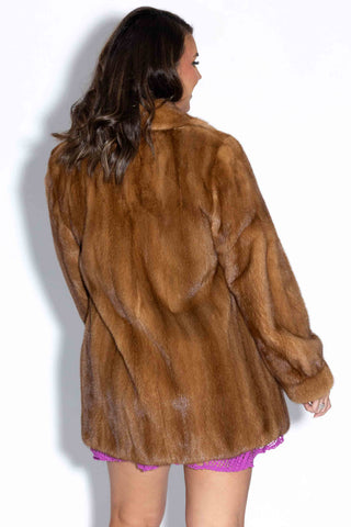 back of woman wearing a whisky mink fur jacket with shawl collar against a white backdrop