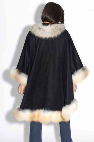 back of woman wearing a black cashmere blend cape with golden island fox fur trim 