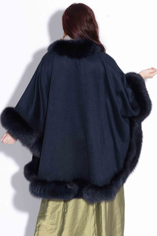 back of woman wearing a navy cashmere blend cape with fox fur trim