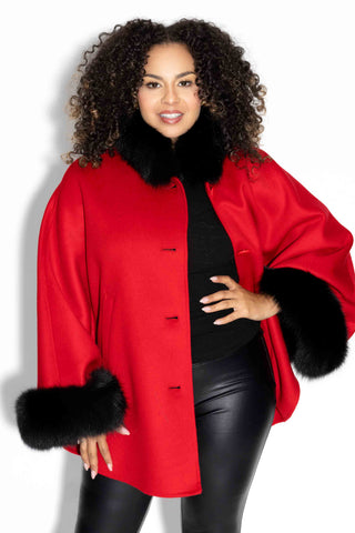 woman wearing a red cashmere & wool blend cape with black fox fur trim against a white backdrop