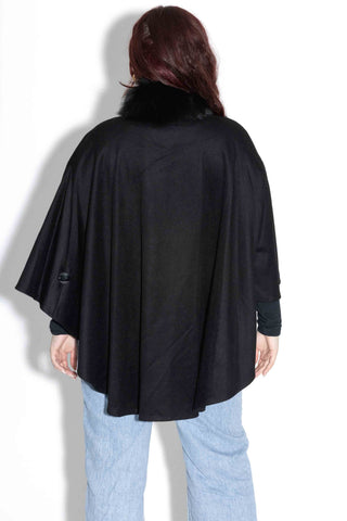 back of woman wearing a black wool blend cape against a white backdrop
