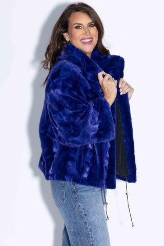 side profile of woman wearing a royal blue sheared sectioned mink fur capelet against a white backdrop