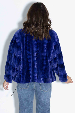 back of woman wearing a royal blue sheared sectioned mink fur capelet against a white backdrop