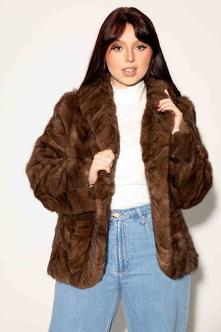 woman wearing a brown sectioned mink fur bolero jacket against a white backdrop