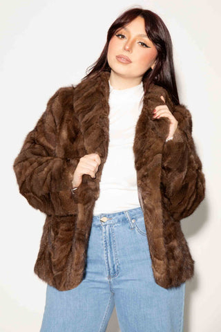 woman wearing a brown sectioned mink fur bolero jacket against a white backdrop