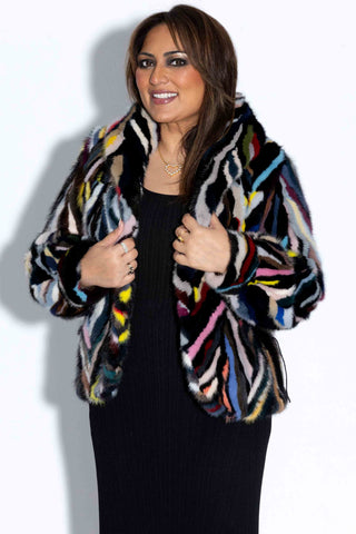 smiling woman wearing a multicolor sectioned mink fur bolero jacket against a white backdrop