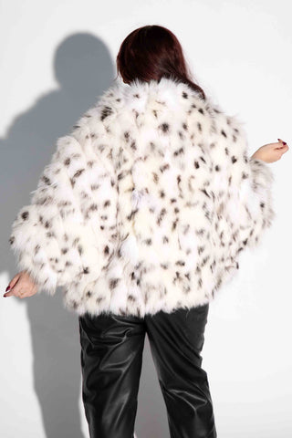 back of woman wearing a white with black sectioned fox fur cape against a white backdrop