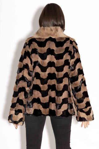 back of woman wearing a sectioned mink fur jacket with sable fur front against a white backdrop