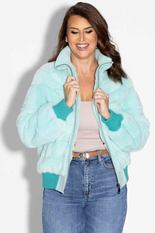 smiling woman wearing a mint nafa mink fur jacket against a white backdrop