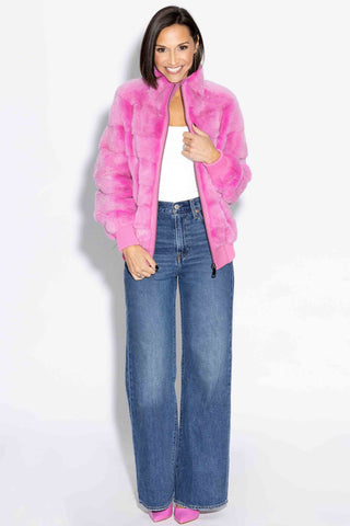 smiling woman wearing a pink nafa mink fur jacket with horizontal pattern against a white backdrop