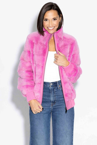 closeup view of smiling woman wearing a pink nafa mink fur jacket with horizontal pattern against a white backdrop