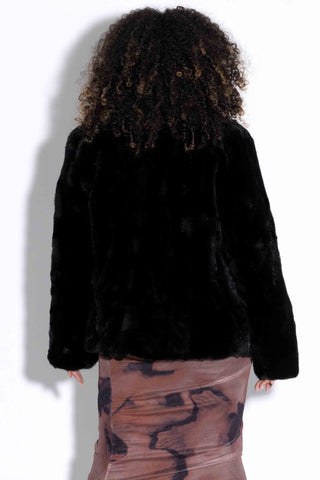 back of woman wearing a reversible ranch sectioned mink fur jacket against a  white backdrop