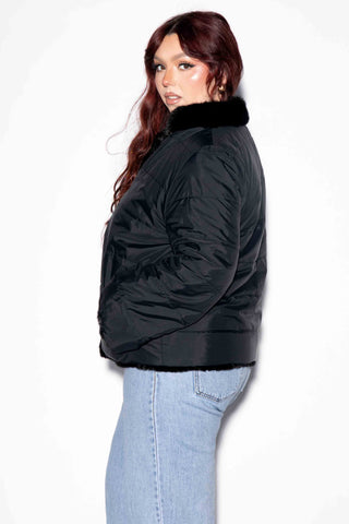 side profile of woman wearing a reversible sectioned mink fur jacket with the down puffy jacket on the outside against a white backdrop