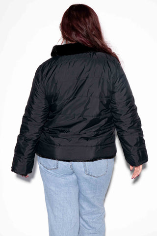 back of woman wearing a reversible sectioned mink fur jacket with the down puffy jacket on the outside against a white backdrop