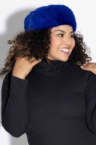 profile of smiling woman wearing a blue mink fur headband against a white backdrop
