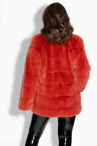 back of woman wearing a paprika mink fur jacket against a white backdrop