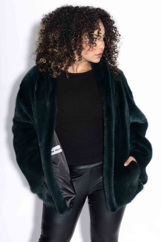 woman wearing evergreen mink velvet full skin mink fur jacket against a white backdrop