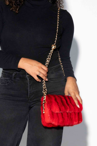 closer view of woman wearing a red mink fur purse against a white backdrop