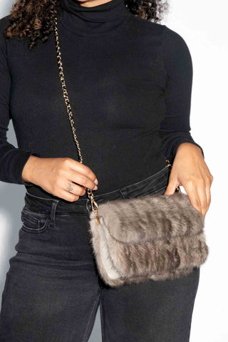 closer view of woman wearing a gray mink fur purse against a white backdrop