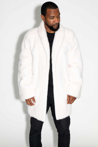 man wearing a white female mink fur stroller against a white backdrop