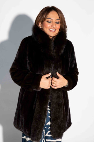 smiling woman wearing a mahogany mink fur stroller with fox fur tux against a white backdrop