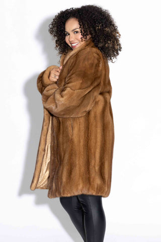 side profile of smiling woman wearing a whisky mink fur stroller with shawl collar against a white backdrop