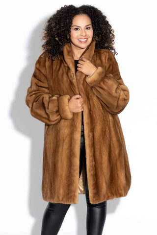 smiling woman wearing a whisky mink fur stroller against a white backdrop