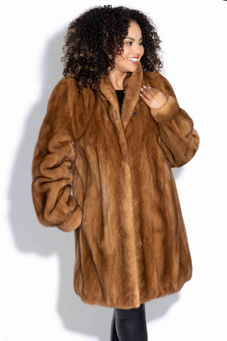 smiling woman wearing a whisky mink fur stroller with a shawl collar against a white backdrop