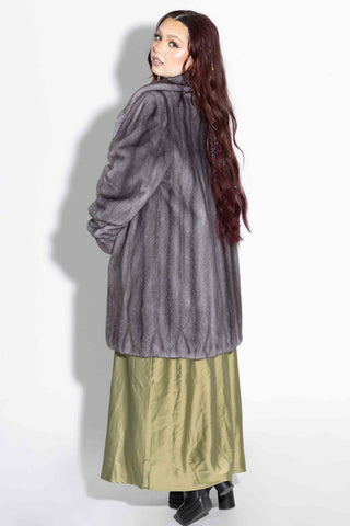 side profile of woman wearing a blue iris mink fur stroller with shawl collar against a white backdrop