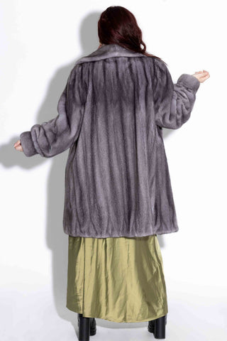 back of woman wearing a blue iris mink fur stroller with shawl collar against a white backdrop