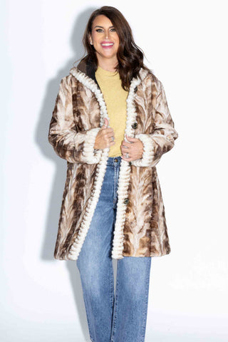 smiling woman wearing a beige cross reversible sheared sectioned mink fur stroller with hood against a white backdrop