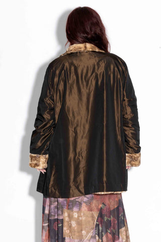 back of woman wearing a beige cross reversible sheared sectioned mink fur stroller against a white backdrop