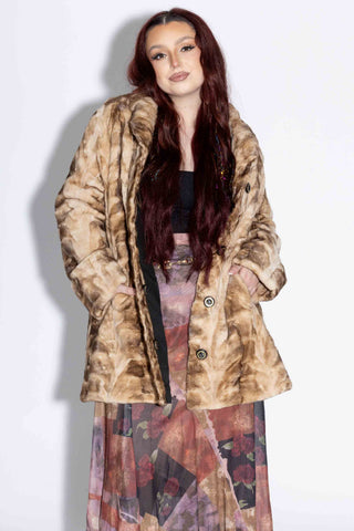 woman wearing a beige cross reversible sheared sectioned mink fur stroller against a white backdrop