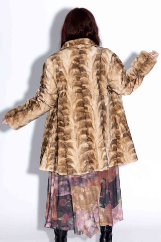 back of woman wearing a beige cross reversible sheared sectioned mink fur stroller against a white backdrop